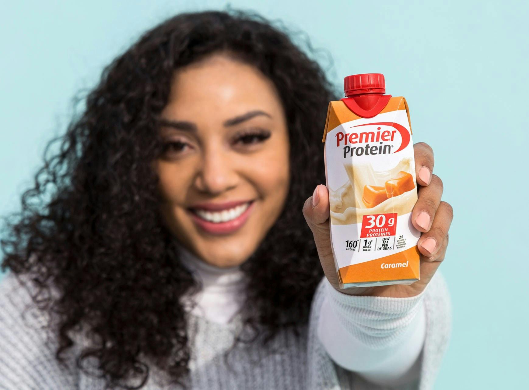 A women holding a Caramel protein shake.