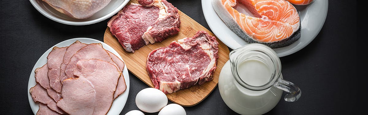 Plates full of meat, fish and a bowl of milk.