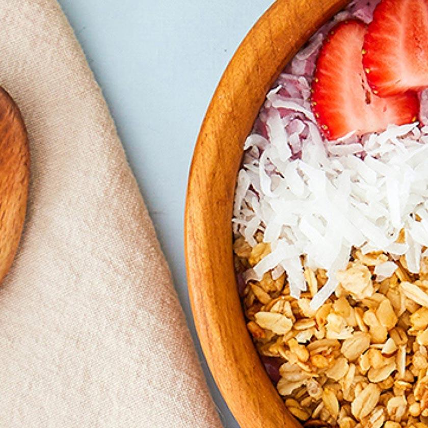A healthy bowl of granola with coconut and strawberries.