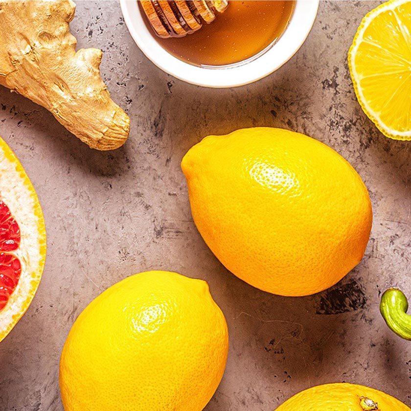 A few lemons, a piece of ginger and small bowl of honey.