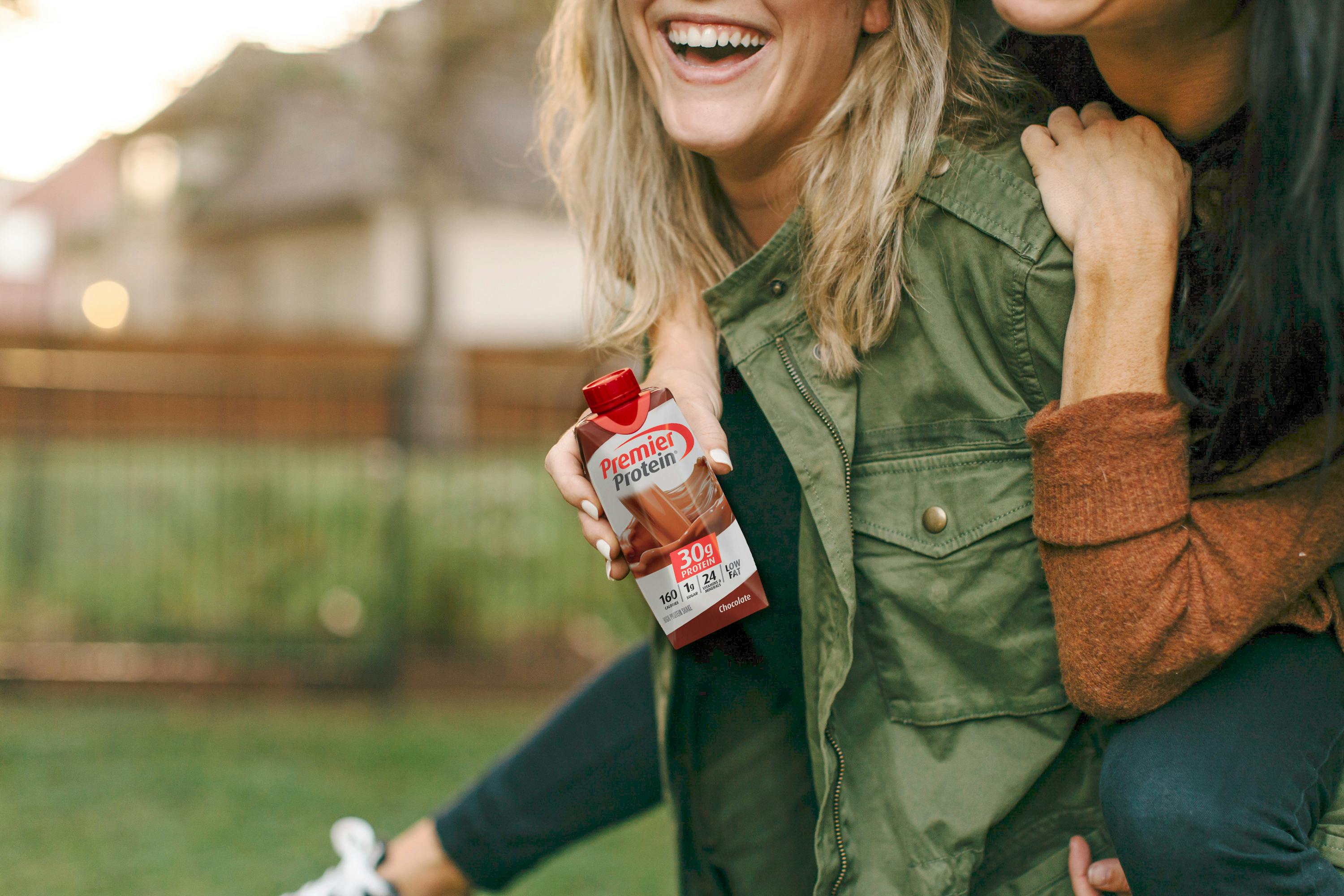 Two girls holding a Canadian Chocolate Premier Protein Drink