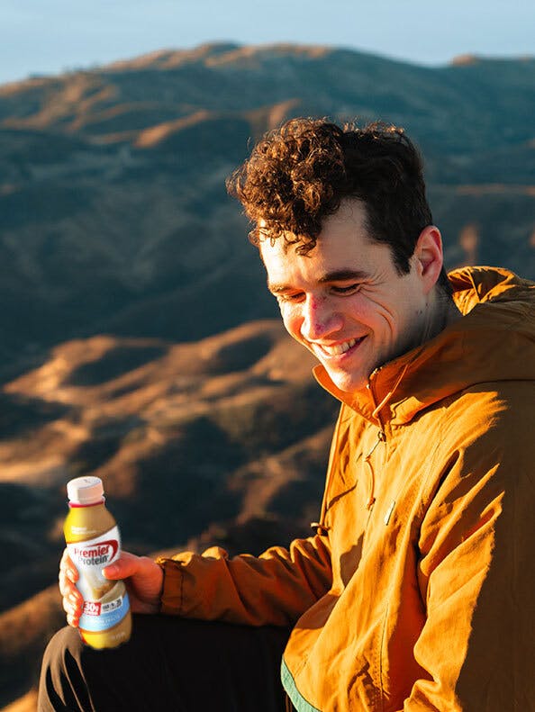A hiker enjoying a premier protein shake at an overlook