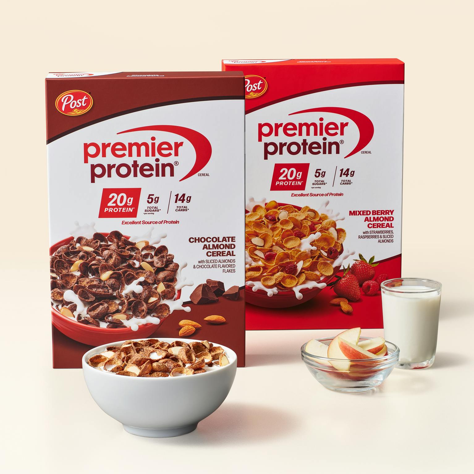 Two boxes of Premier Protein cereal, a bowl of Premier Protein cereal, a bowl of apple slices and a glass of delicious milk.